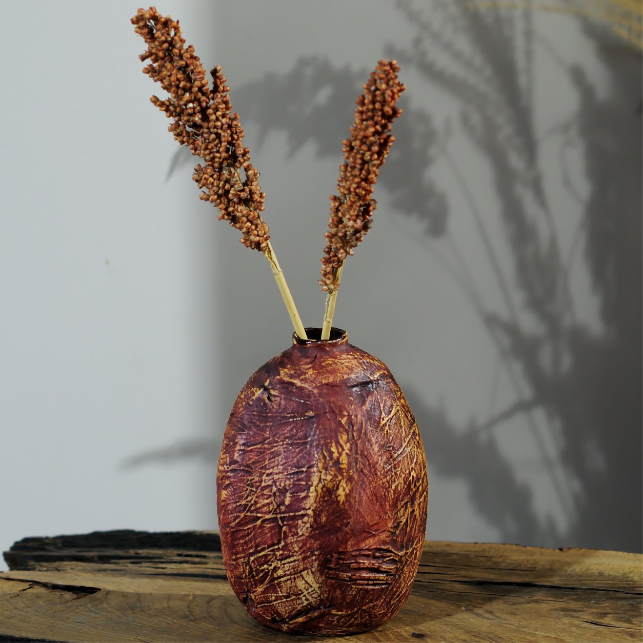 Sculptural ceramic vase styled on wooden shelf in modern interior setting