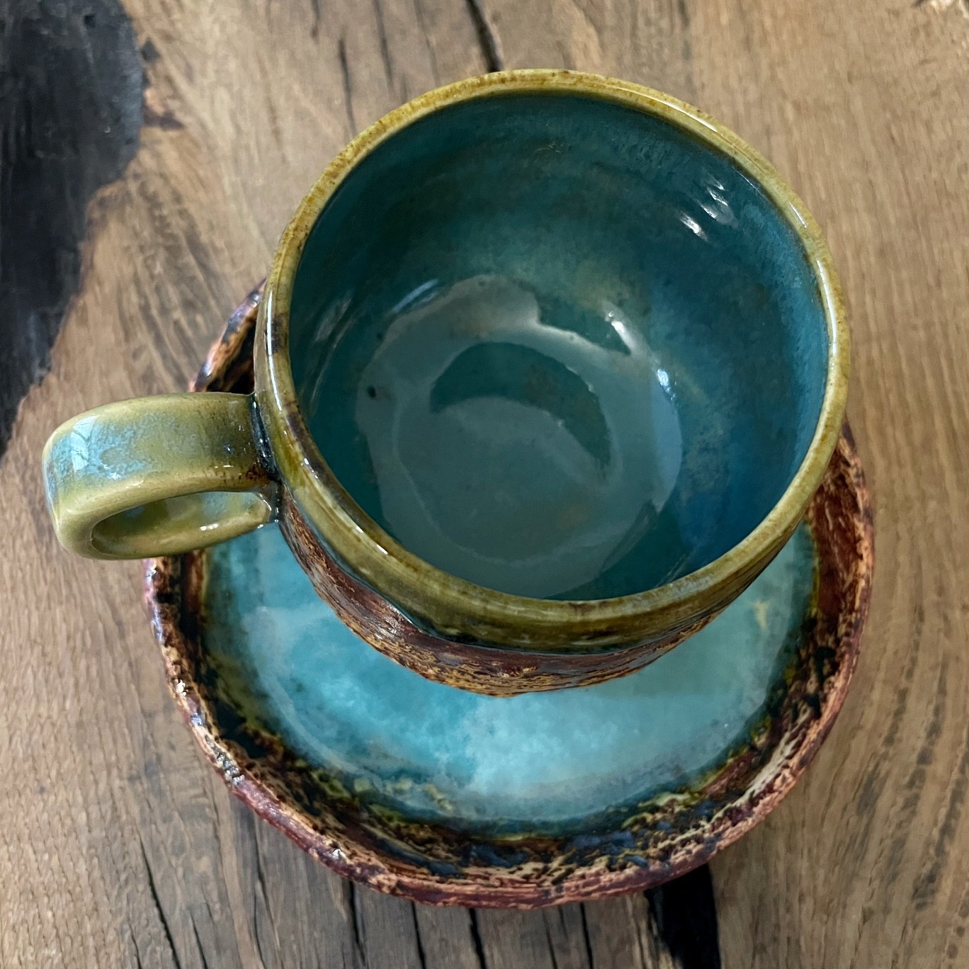 Stoneware coffee cup and saucer with blue and green glaze details