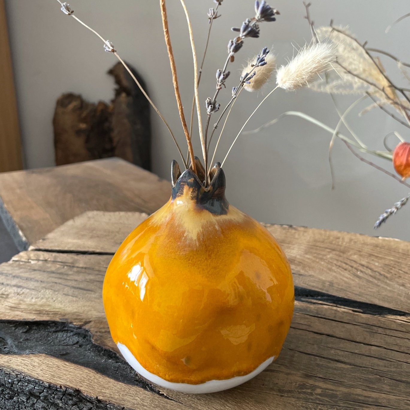 Decorative ceramic pomegranate on wooden table, vibrant yellow glaze with soft organic form