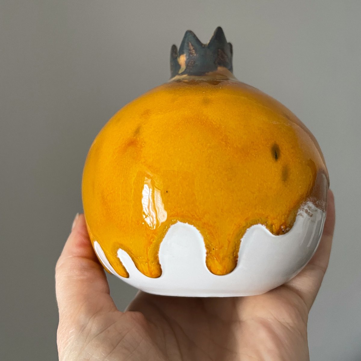 Bright yellow ceramic pomegranate sculpture with dripping glaze effect, handcrafted pottery decor