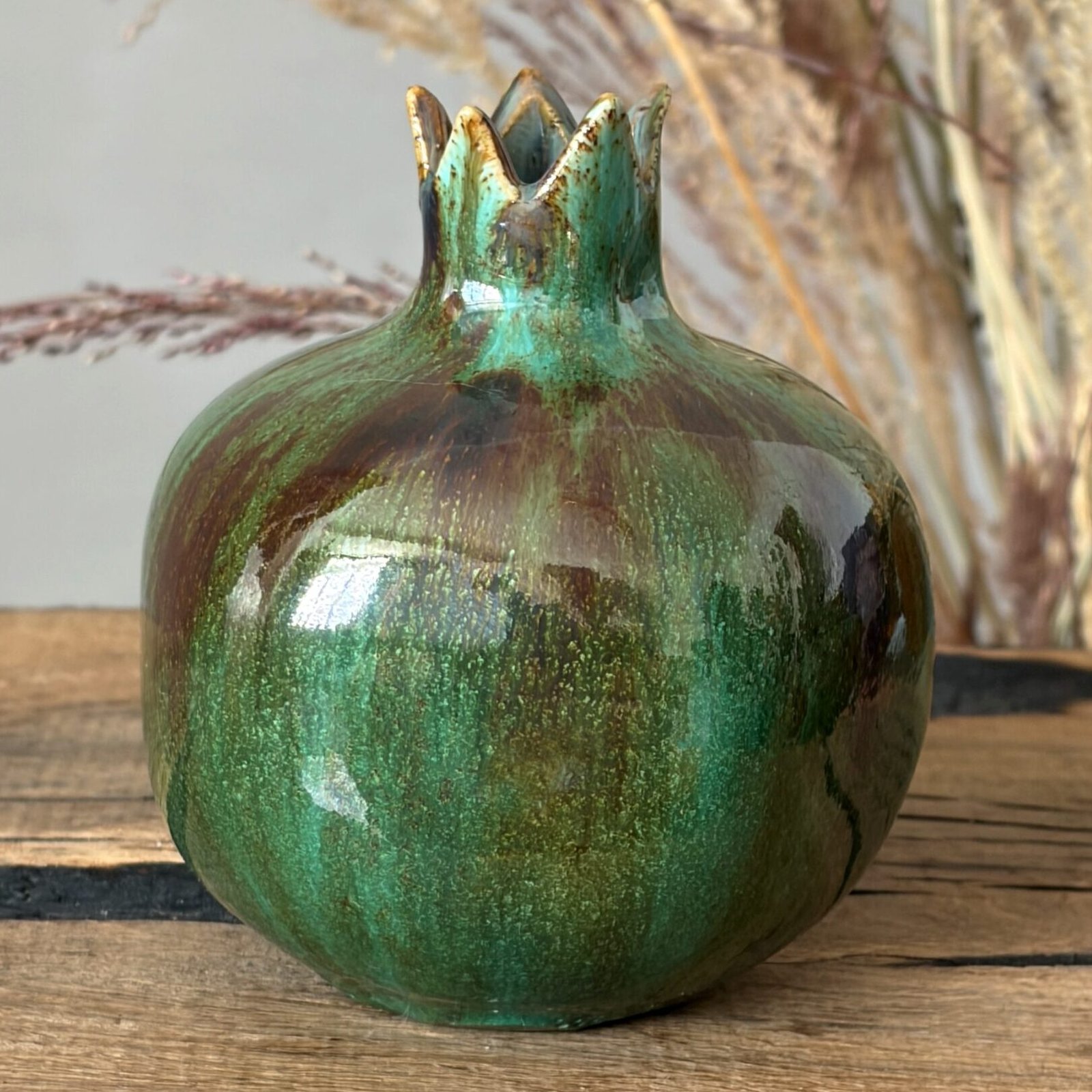 Artisan ceramic pomegranate with glossy green finish and handmade texture