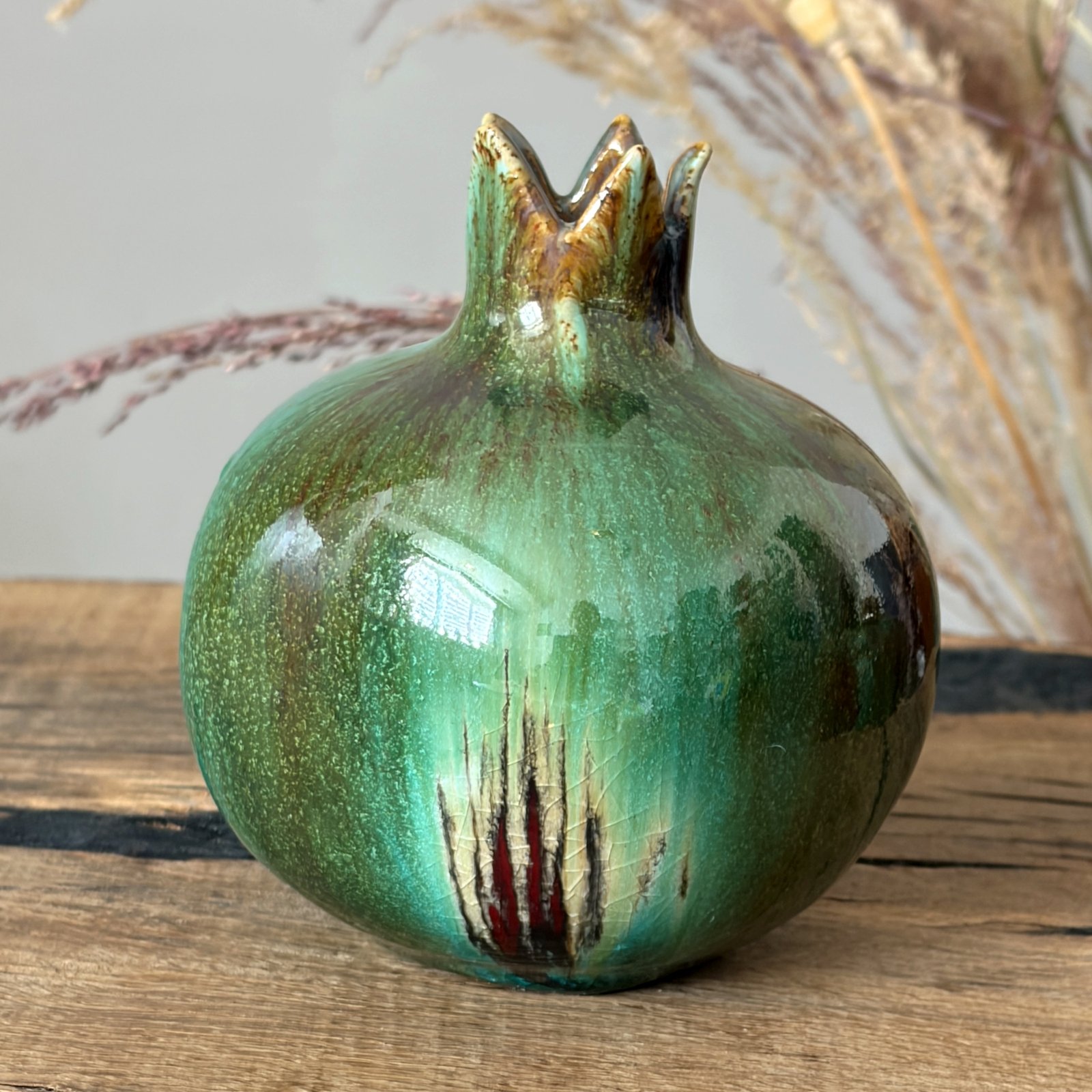 Handcrafted pottery pomegranate showing natural green glaze variations