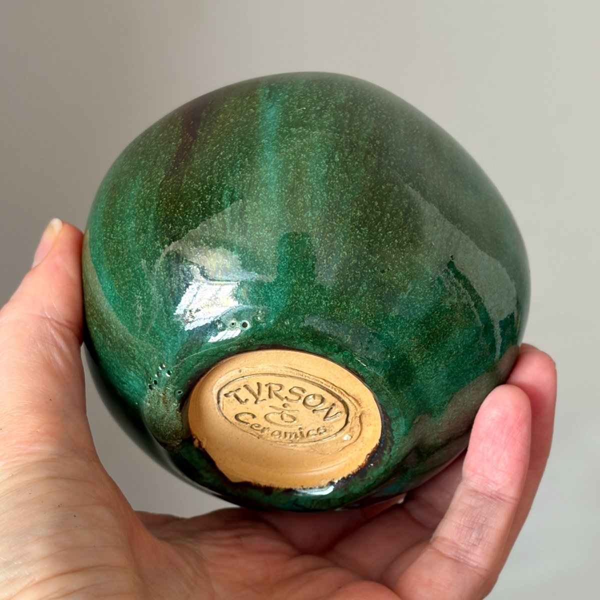 Handmade green ceramic pomegranate vase held in hand