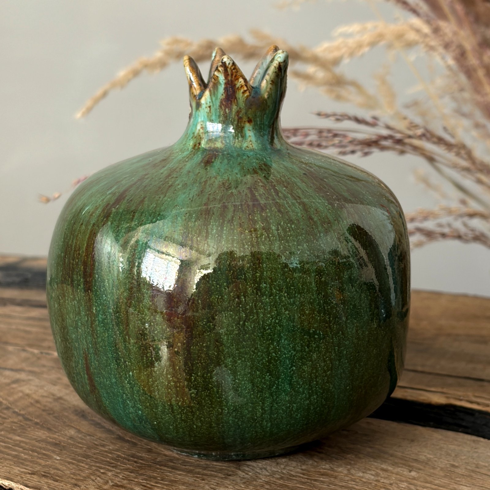 Handcrafted pottery pomegranate with flowing green glaze variations