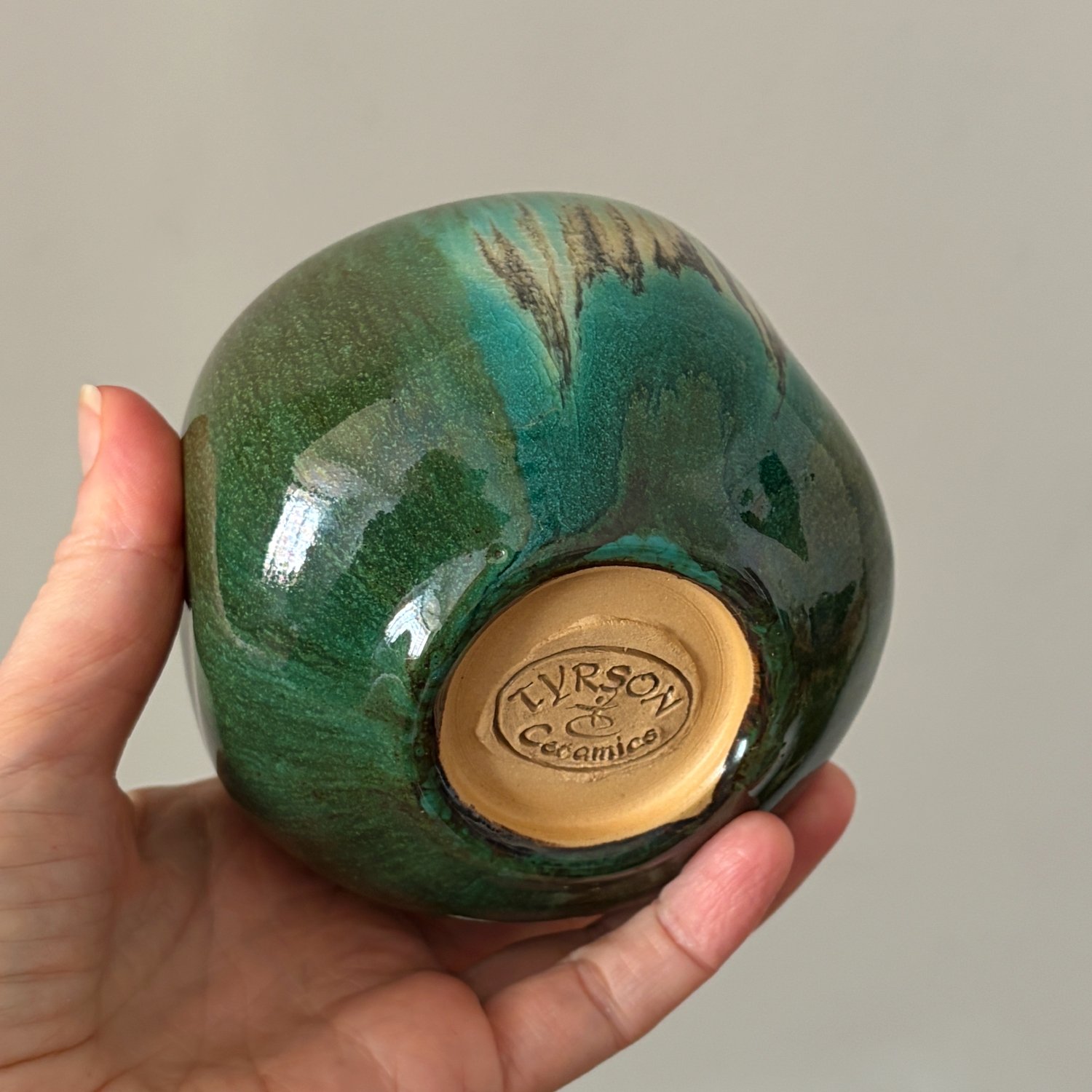 Ceramic pomegranate held in hand showing its glazed base