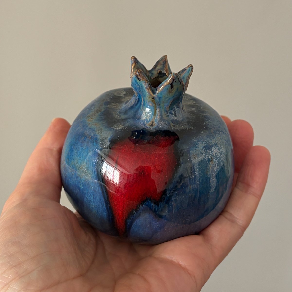 Artisan pottery pomegranate with blue glazed body and vivid red detail