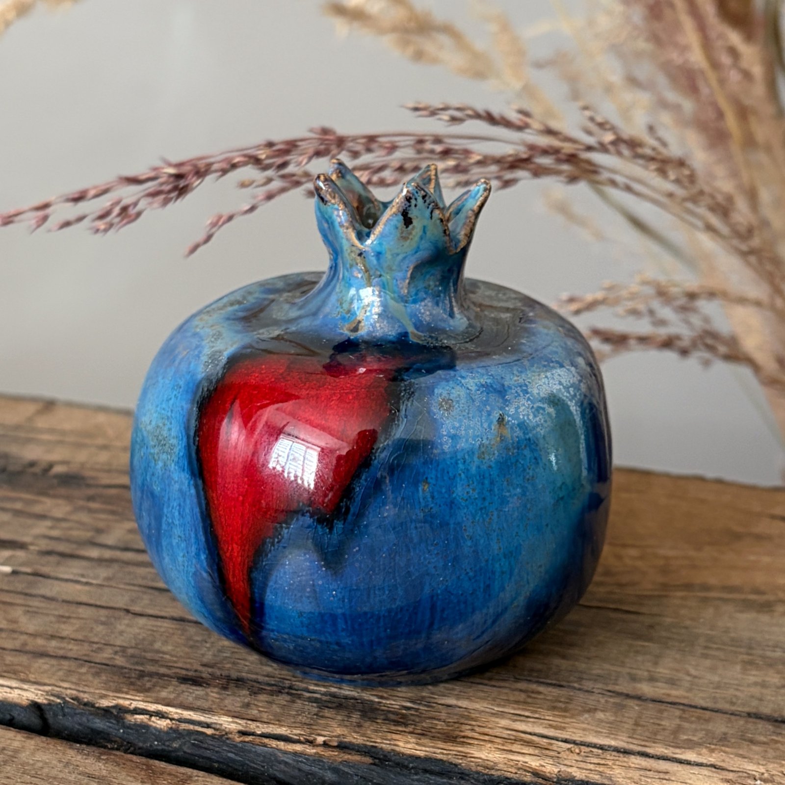 Ceramic pomegranate vase with blue glaze and contrasting red accent