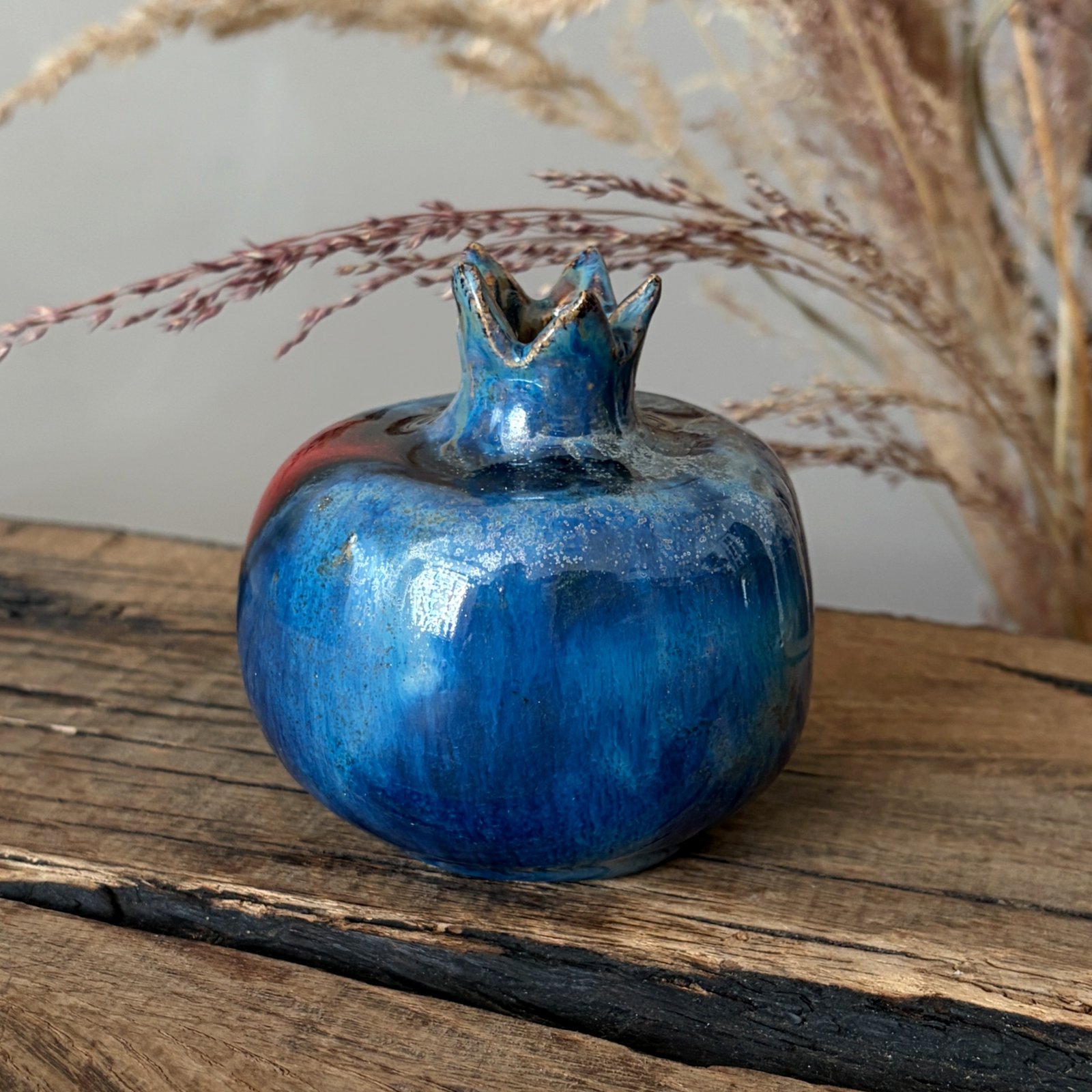 Glazed pottery pomegranate with deep blue finish and sculpted crown