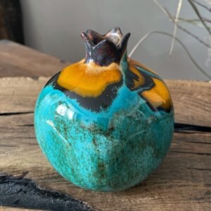 Artistic ceramic pomegranate sculpture with glossy yellow top and textured turquoise surface
