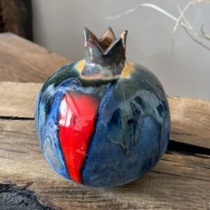 Blue glazed ceramic pomegranate with contrasting red element, artisan home decor piece