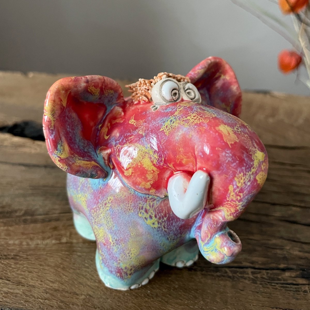 Funny whimsical elephant ceramic statue with large cartoon eyes and white tusks