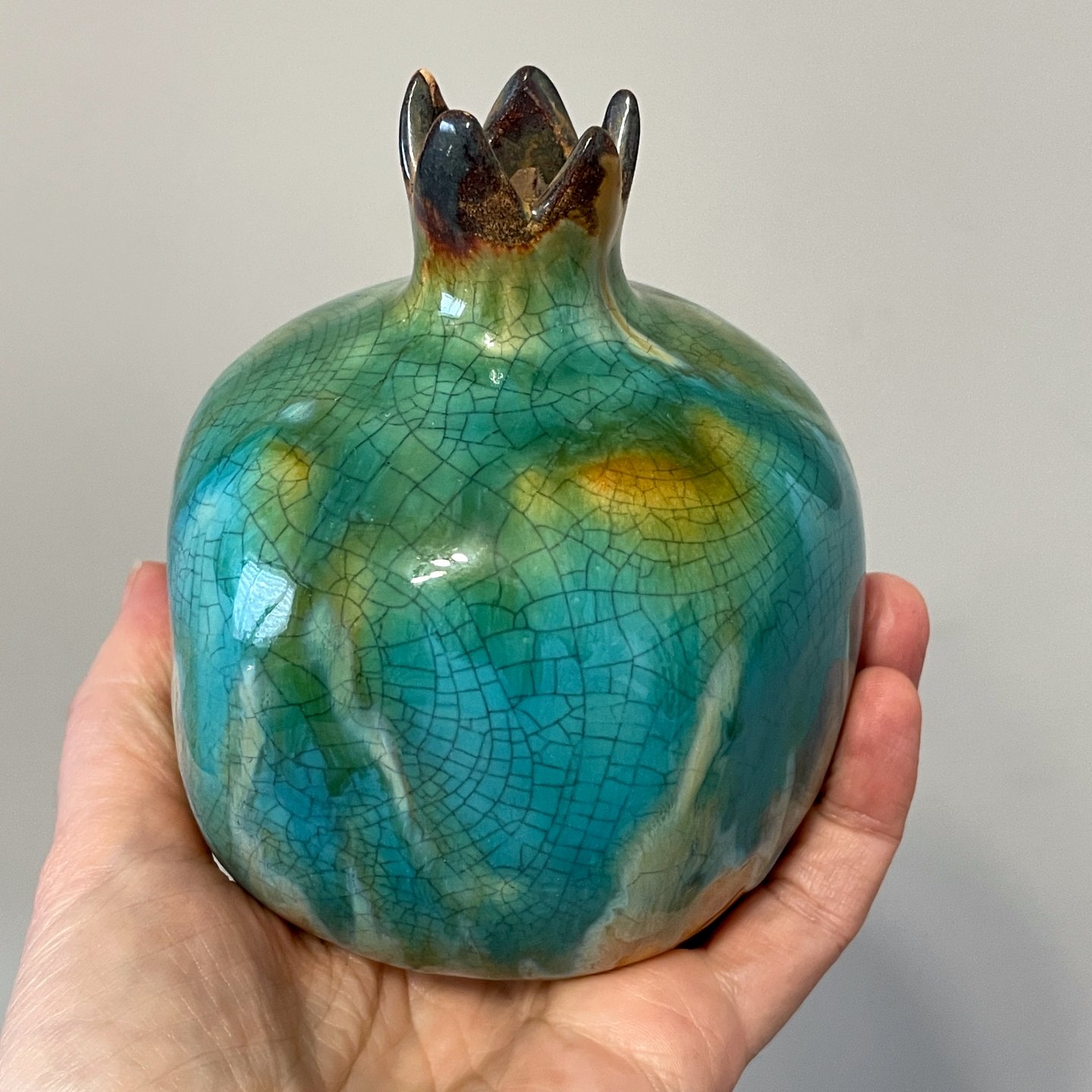 Front view of ceramic pomegranate vase held in hand