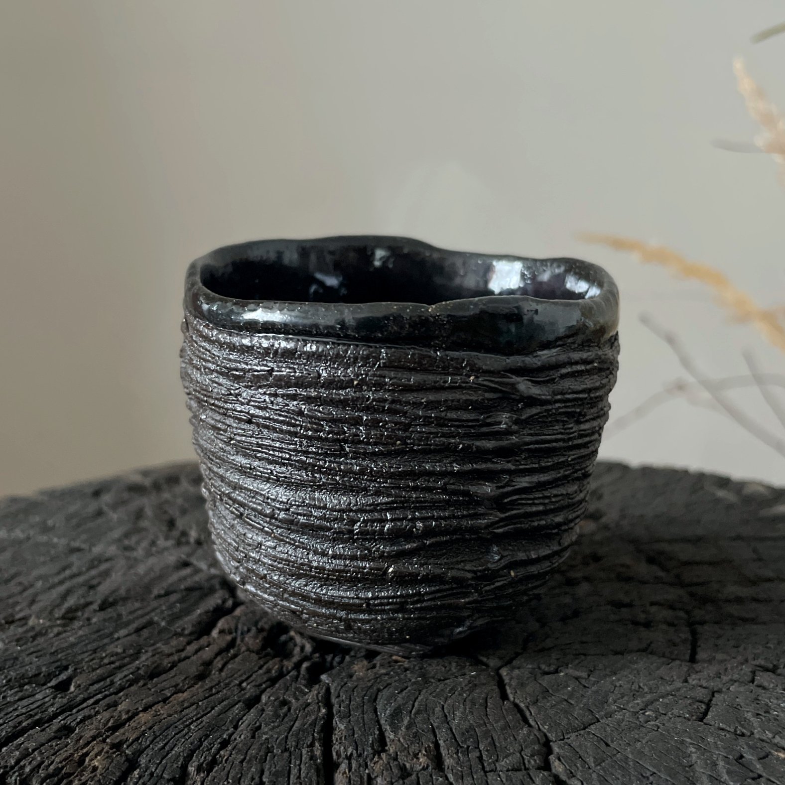 Handmade ceramic yunomi tea cup with textured black stoneware surface
