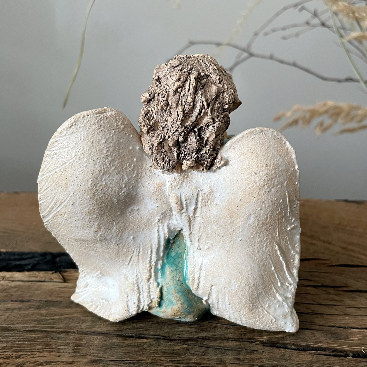 Back view of handmade ceramic angel with white wings