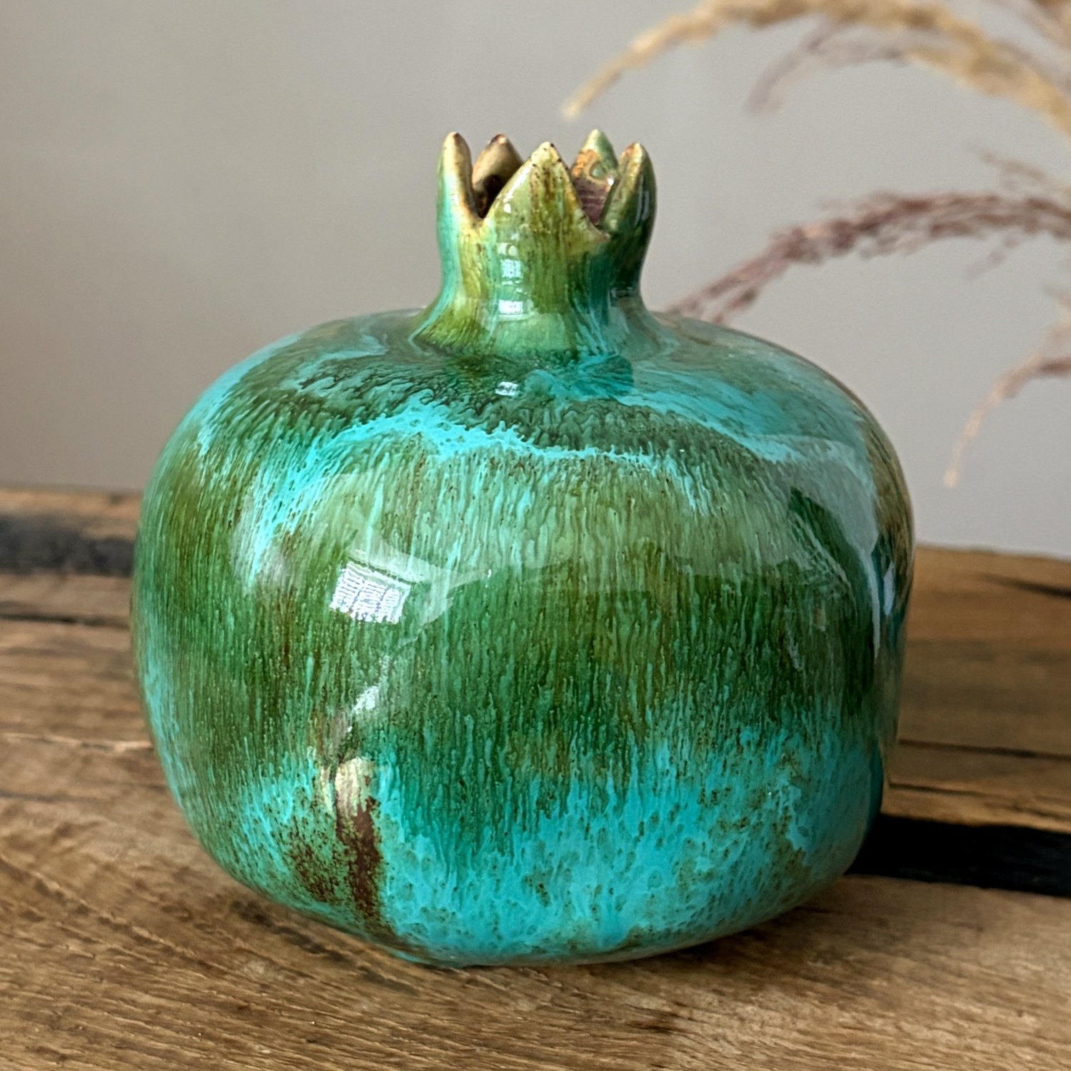Close-up of handmade ceramic pomegranate with textured turquoise green glaze