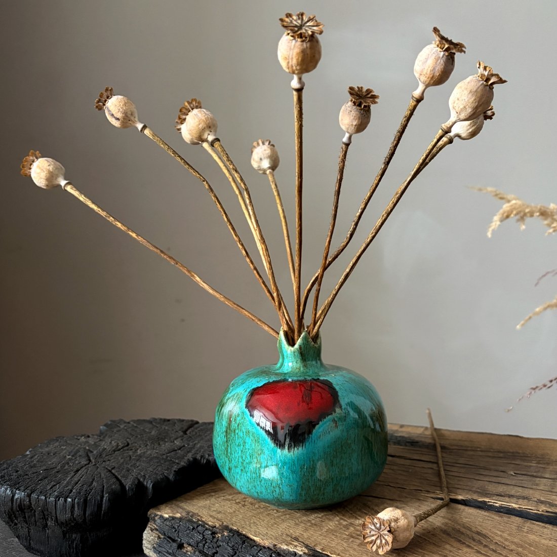 Handmade pottery pomegranate with decorative dried stems and turquoise glaze