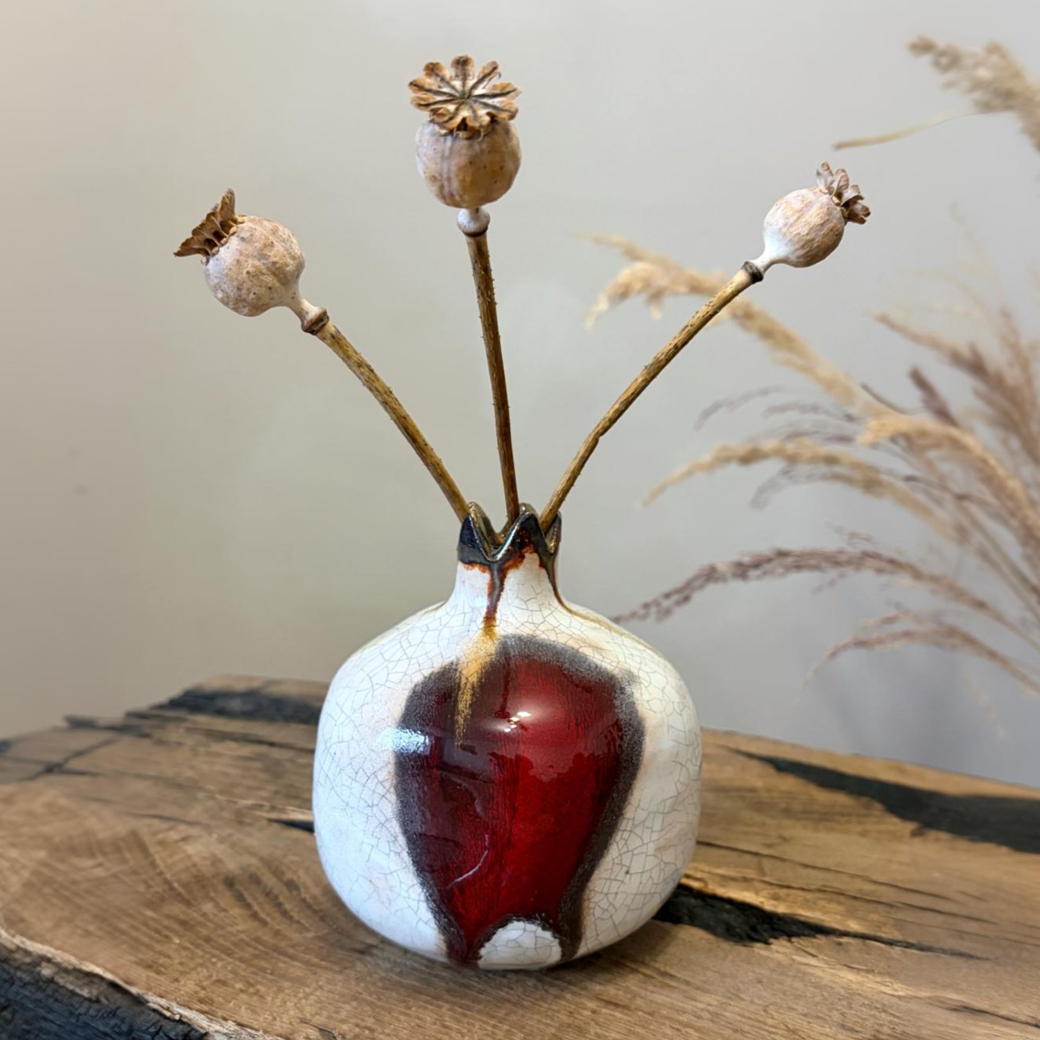 Decorative ceramic pomegranate displayed with dried botanical stems