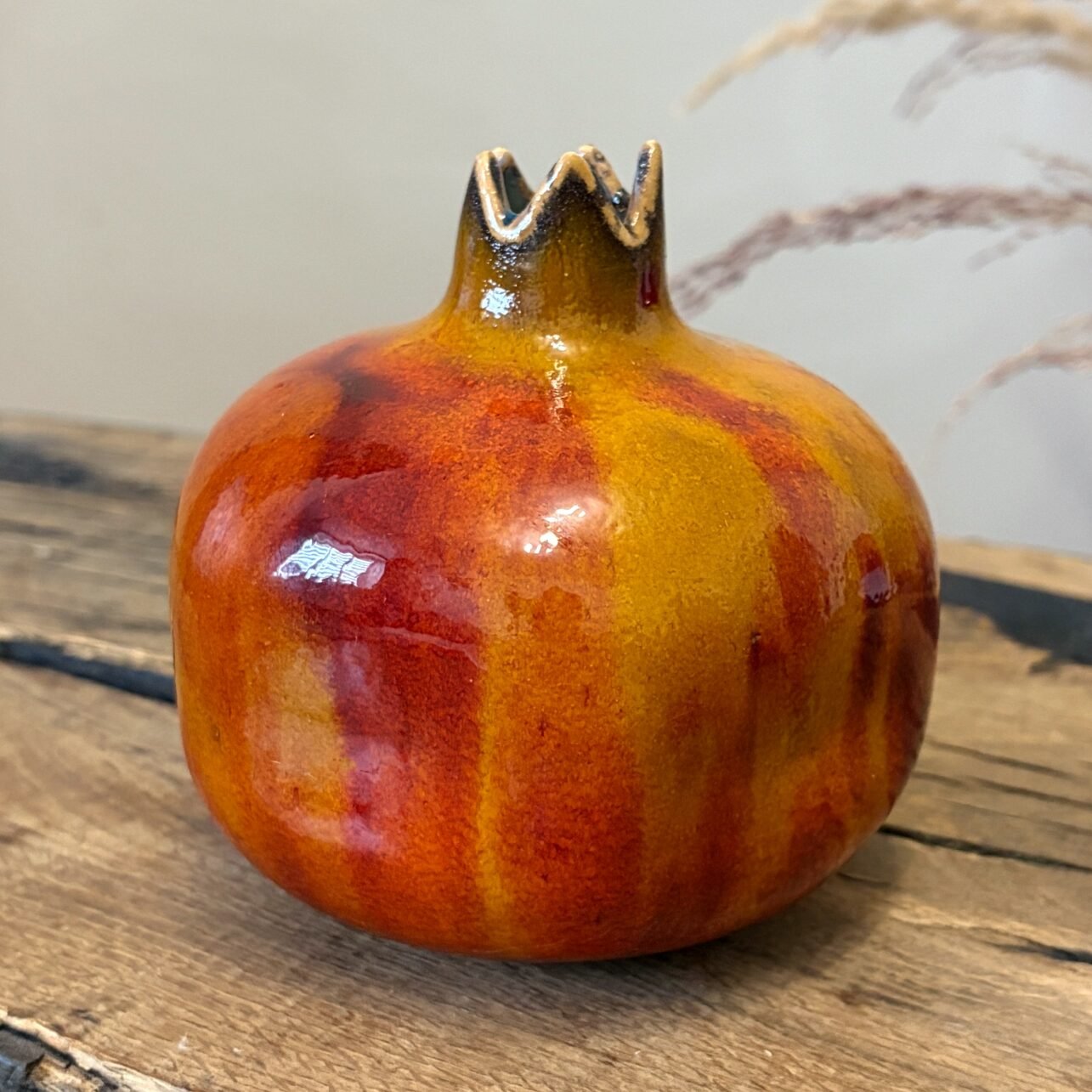 Close-up of ceramic pomegranate with vibrant orange and red glazed surface