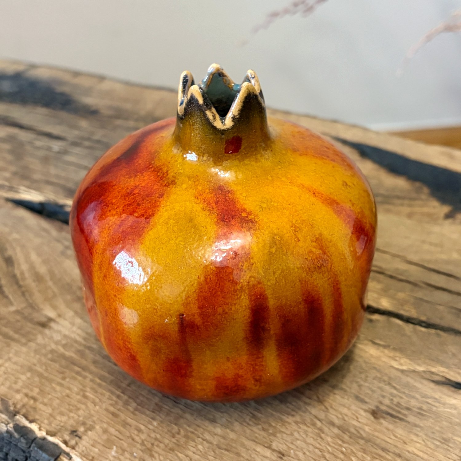 Glazed pottery pomegranate with rich yellow, orange and red tones