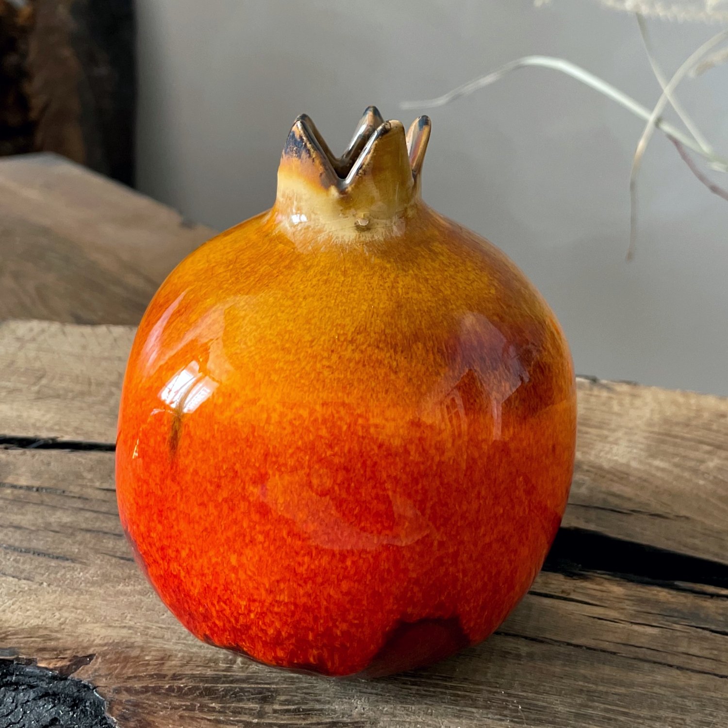 Handcrafted ceramic pomegranate with vibrant red and amber glaze