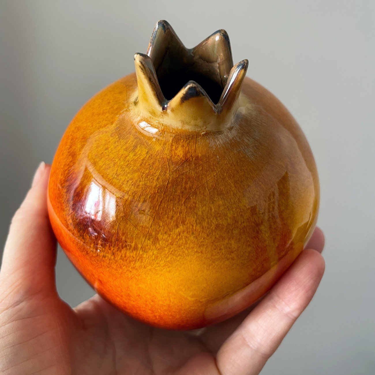 Handmade ceramic pomegranate sculpture with glossy red orange glaze
