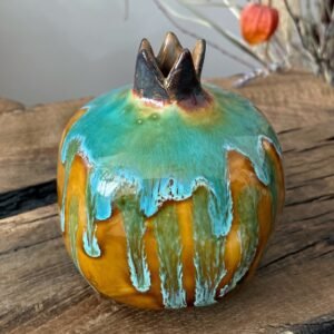 Handmade ceramic pomegranate vase with turquoise drip glaze on wooden table