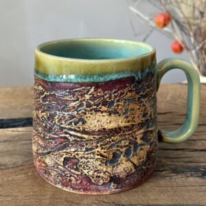 Large handmade pottery mug with earthy texture and green glazed interior