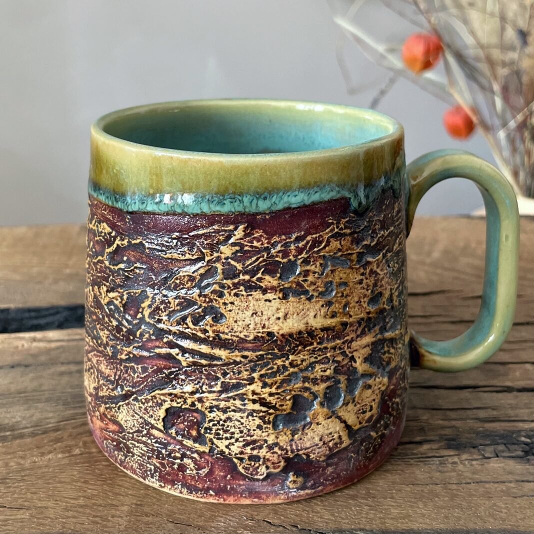 Large handmade pottery mug with earthy texture and green glazed interior
